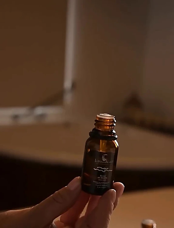 Una mano sostiene un frasco de aceite para aromaterapia en la cabina de masaje
