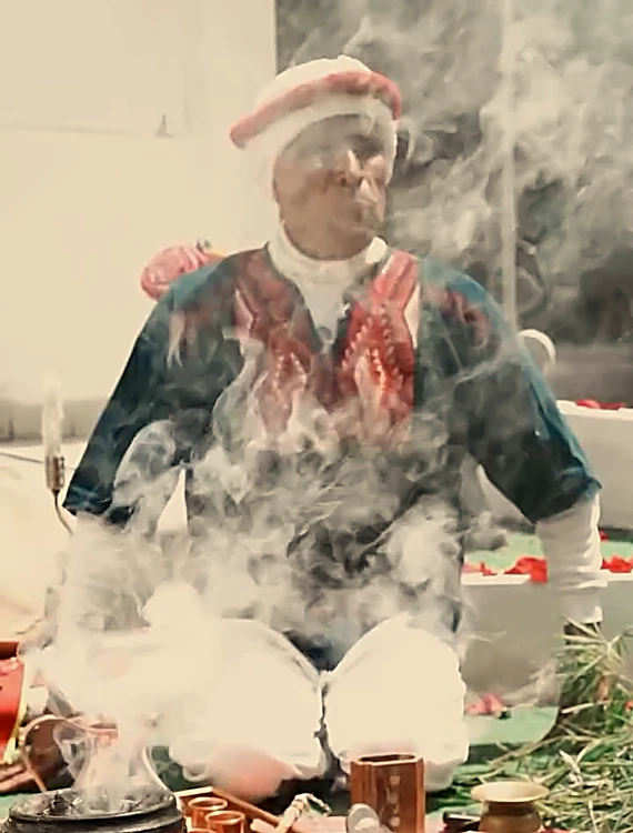 El guía del temazcal sentado frente al altar mientras el humo de copal sube del sahumador