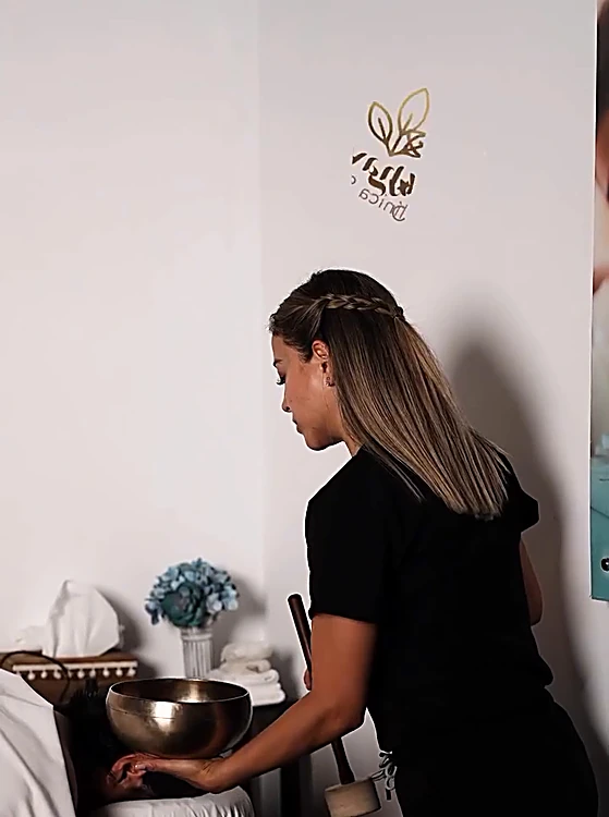 Una terapeuta de Sukhavati prepara un cuenco tibetano junto a la camilla de masaje