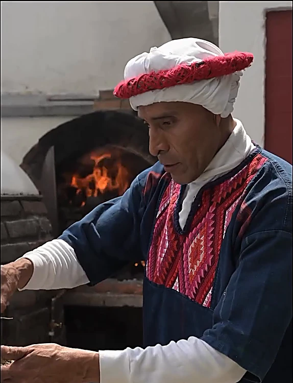 El guía del temazcal, con turbante rojo y blanco y camisa bordada, junto al horno donde arde el fuego