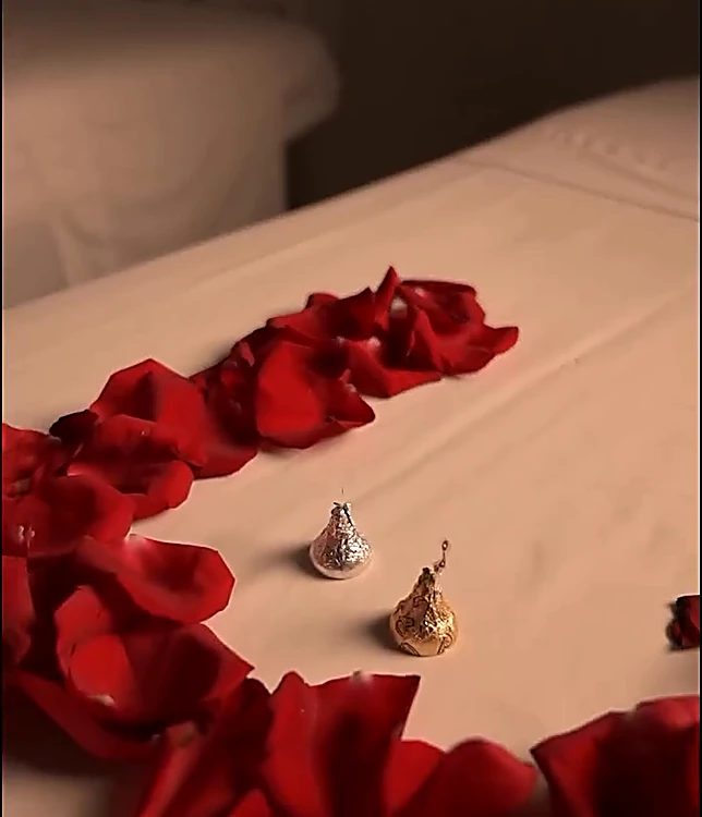 Pétalos de rosa roja y dos chocolates sobre la camilla de una cabina