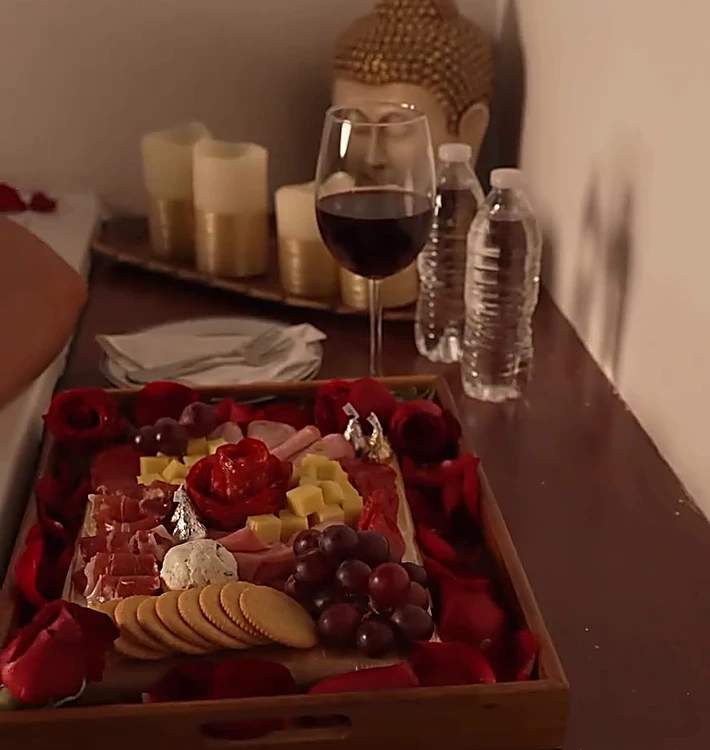 Tabla de quesos, carnes frías y fruta con copa de vino y velas, junto al jacuzzi