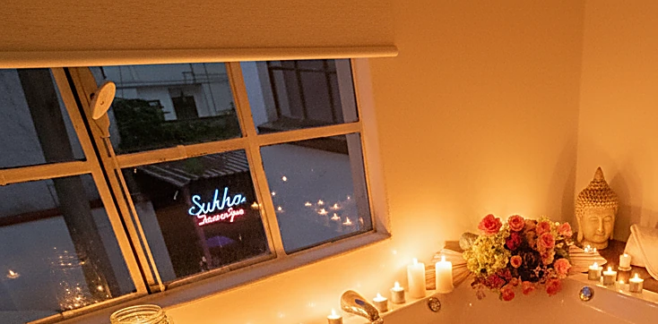 Cabina a la luz de las velas con flores y el letrero de neón de Sukhavati en la ventana